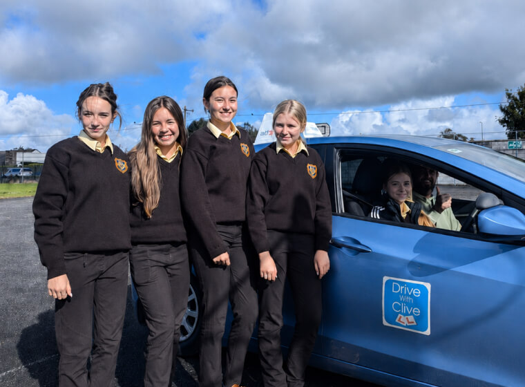 Secondary school students smiling beside the Drive with Clive driving school car