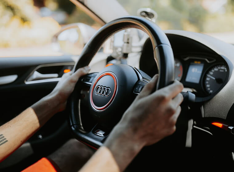 Close-up of a driver holding an Audi steering wheel on the road