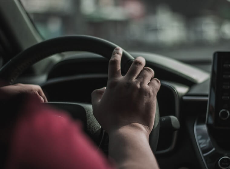 Close-up of a driver holding the steering wheel while driving