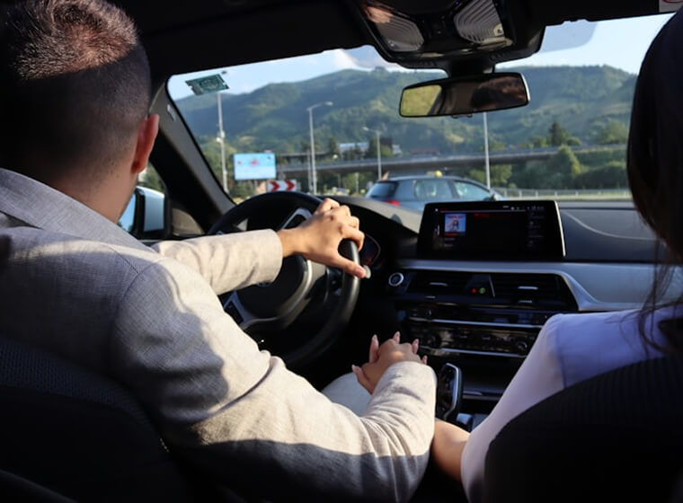 Driver practicing on a rural road with countryside visible ahead